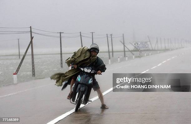 Motorcyclist fights against strong wind as he drives on national highway No 1 in the central province of Ha Tinh 03 October 2007 as tropical typhoon...