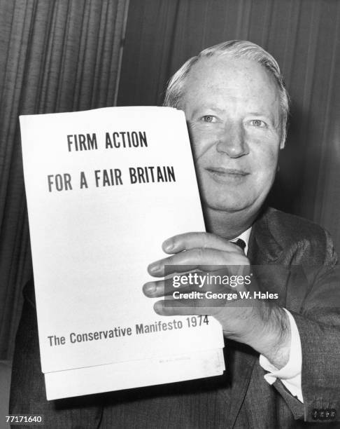 Incumbent British Conservative Prime Minister Edward Heath holding a copy of his party's manifesto at a Conservative Central Office press conference...