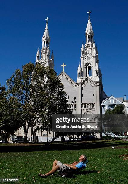 Sunbather enjoys a warm day at Washington Square Park in front of the Saints Peter and Paul Church October 3, 2007 in the North Beach neighborhood of...