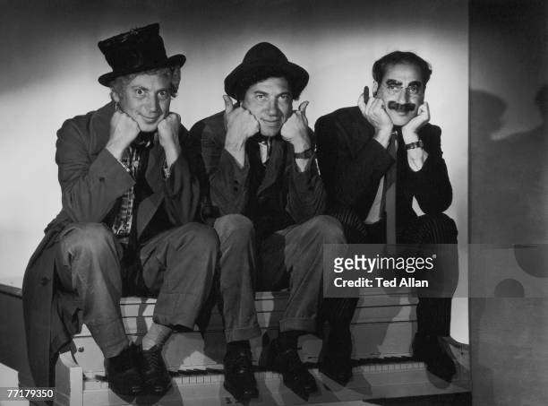 The Marx Brothers perch side by side on a piano, circa 1935.