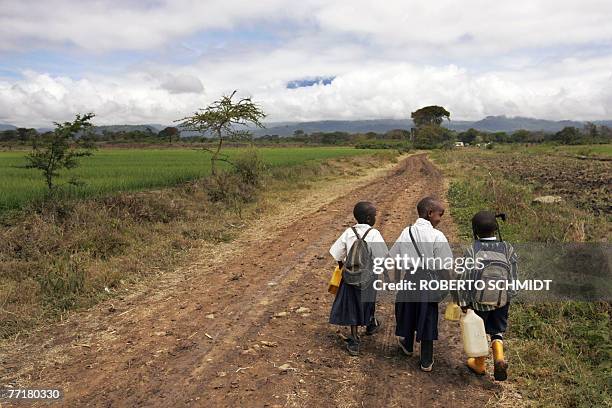 Novesa holds the hand of her five-year-old neighbor Delvin as they and her younger brother Dixon walk down a country road to their school in the Usa...
