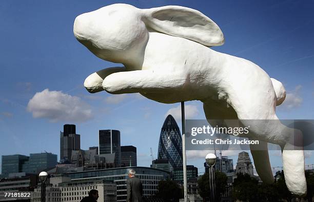 Giant white rabbit appears to vault over the London skyline as part of a collection of giant rabbits on the grass in front of Tower Bridge on October...