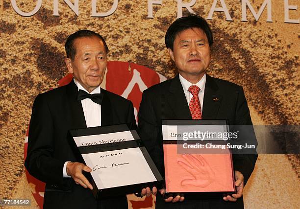 Festival director Kim Dong-Ho, left, and Pusan mayor Huh Nam-Shik hold an autograph and hand print of Ennio Morricone at the opening ceremony of the...