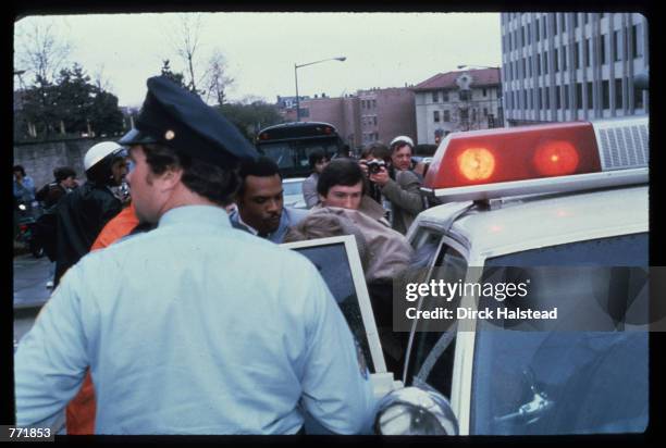 Authorities place John Hinkley Jr. Into a police car shortly after his attempt to assassinate President Reagan on March 30, 1981 outside the Hilton...