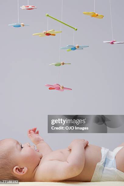 a baby playing with a mobile - using mobile stockfoto's en -beelden