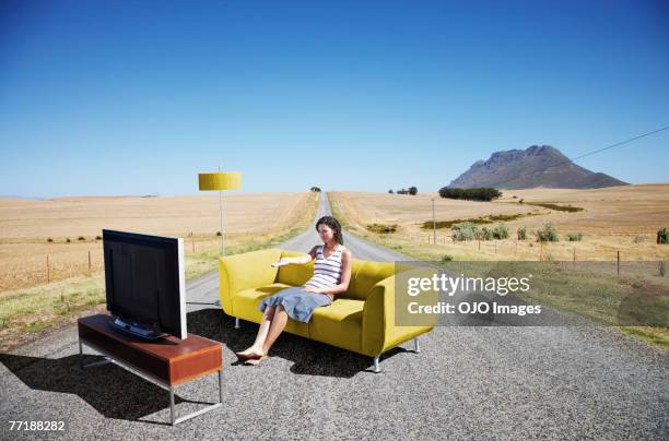 a woman watching television on a couch in the road - out of context stock pictures, royalty-free photos & images