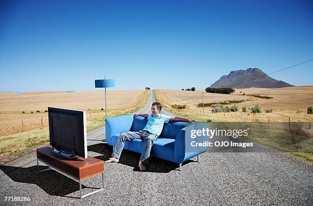 a man watching television on a couch in the road - crazy stock pictures, royalty-free photos & images