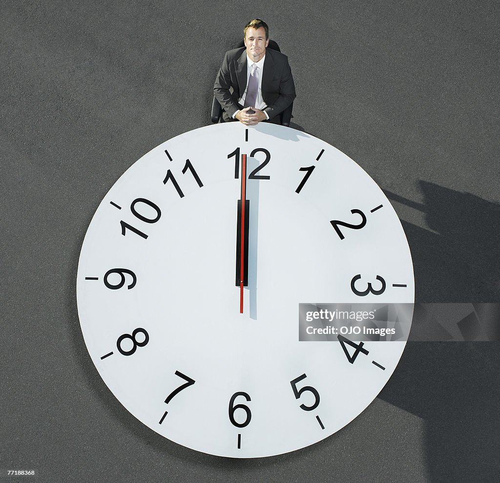 A businessman sitting at a clock table