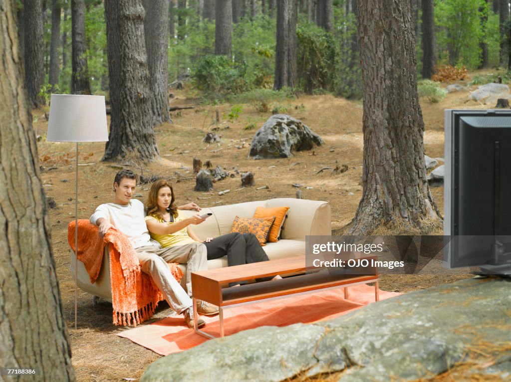 A couple watching television outdoors in the woods