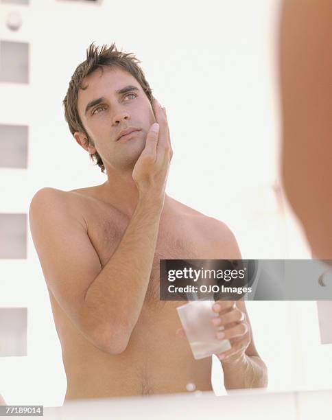 a man applying aftershave - aftershave stock pictures, royalty-free photos & images