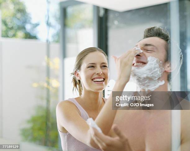 a woman helping a man shave - shaving cream stock pictures, royalty-free photos & images