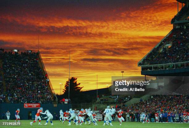 John Friesz, Quarterback for the Seattle Seahawks takes the snap on the line of scrimmage and prepares to throw downfield under a golden sunset sky...