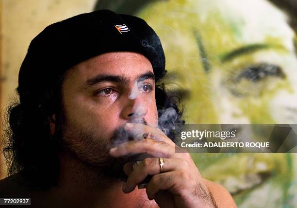 Cuban artist Javier Guerra smokes in front of a recent work depicting legendary Argentinian-born guerrilla leader Ernesto "Che" Guevara, 03 October...