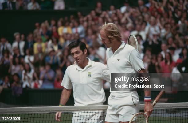 Australian tennis player Ken Rosewall embraces American tennis player Stan Smith at the net after defeating him 6-8, 4-6, 9-8, 6-1, 6-3 in the...