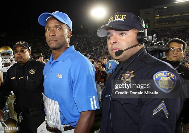 Head Coach Karl Dorrell of the UCLA Bruins walks off the field with security after his team's 20-6 upset loss to the Notre Dame Fighting Irish during...