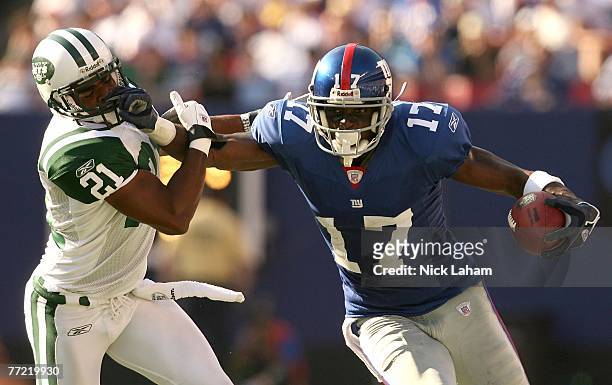 Plaxico Burress of the New York Giants pushes off the tackle of Andre Dyson of the New York Jets on his way to a touchdown in the fourth quarter at...
