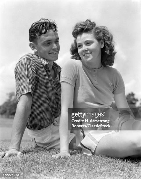 1930s 1940s PORTRAIT SMILING TEENAGE COUPLE BOY GIRL SITTING IN GRASS