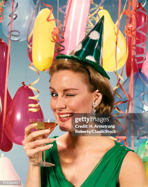 1960s BLOND WOMAN CELEBRATING NEW YEARS WEARING PARTY PAPER HAT DRINKING CHAMPAGNE LOOKING AT CAMERA WINKING EYE