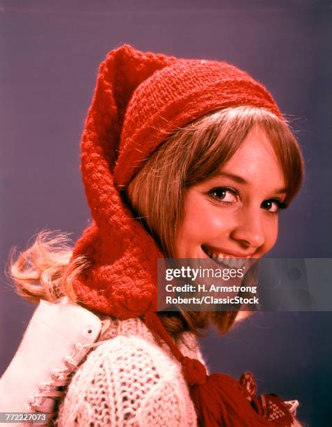 1960s SMILING YOUNG WOMAN WITH ICE SKATES WOOL HAT AND SWEATER LOOKING AT CAMERA