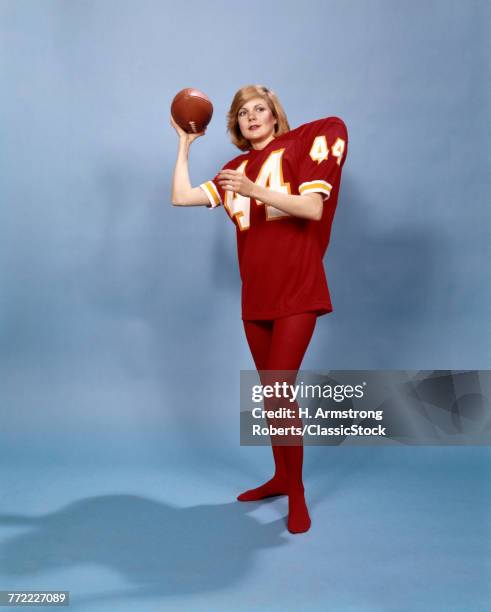 1970s BLOND WOMAN WEARING RED EXTRA LARGE FOOTBALL JERSEY NUMBER 44 RED TIGHTS ABOUT TO PASS FOOTBALL