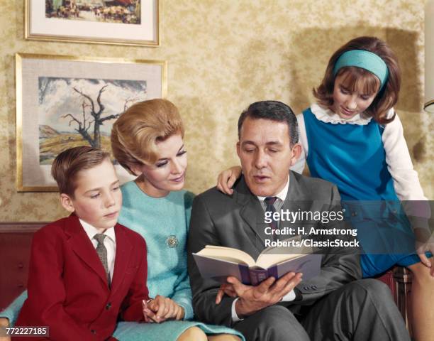 1960s FATHER READING TO HIS FAMILY MOTHER SON AND DAUGHTER