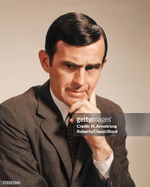1960s PORTRAIT MAN WITH SERIOUS FACIAL EXPRESSION HAND AT CHIN HEAD DOWN LOOKING AT CAMERA