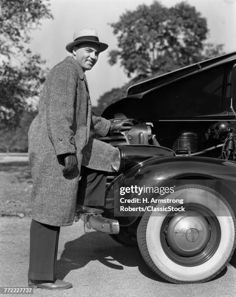 1930s 1940s SMILING MAN FOOT UP ON BUMPER HOOD OPEN DISPLAYING PROUDLY THE ENGINE OF THE CAR WEARING COAT HAT GLOVES
