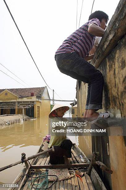 Man climbs up a wall to get in his flooded house in Thach Thanh district, in the central province of Thanh Hoa, 08 October 2007. At least 58 people...