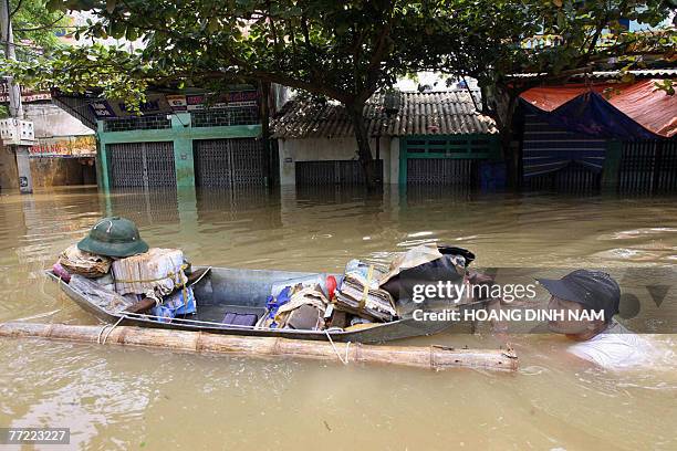 Man swims as he pushes a boat carrying his belongings, in a flooded street in Thach Thanh district, in the central province of Thanh Hoa, 08 October...