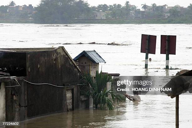 Man swims next to flooded houses along the banks of the Ma river in the central province of Thanh Hoa, 05 October 2007, after Typhoon Lekima hit the...