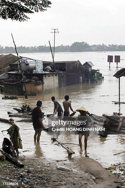 People collect wood for cooking next to flooded houses on the banks of the Ma river in the central province of Thanh Hoa, 05 October 2007, after...