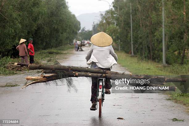 Woman pedals her bicycle carrying firewood after the passage of tropical storm Lekima in the poor central province of Ha Tinh, 04 October 2007....