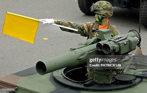 Taiwanese soldier wearing camouflage uniform waves a flag from atop a armoured vehicle equiped with US-made TOW anti-tank missiles as it drives...