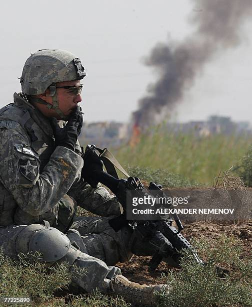 Soldier from Alpha Company, 1/38 Infantry Regiment smokes a cigarette as a fire his unit set to clear undergrowth burns during a clearing operation...