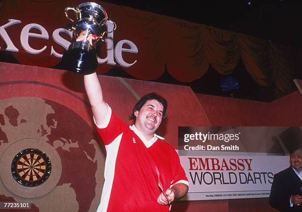 English darts player Phil Taylor lifts the trophy after winning the World Professional Darts Championship at the Lakeside Country Club at Frimley...