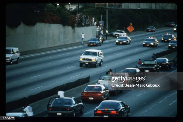 Motorists stop and wave as police cars pursue the Ford Bronco driven by Al Cowlings, carrying fugitive murder suspect O.J. Simpson, on a 90-minute...