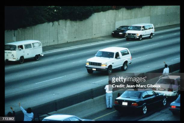 Motorists wave as police cars pursue the Ford Bronco driven by Al Cowlings, carrying fugitive murder suspect O.J. Simpson, on a 90-minute slow-speed...