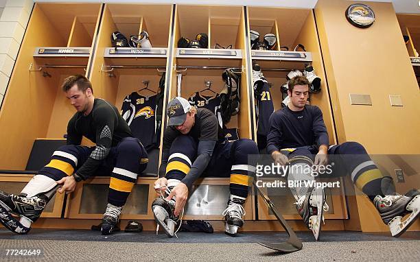 Nathan Paetsch, Thomas Vanek, and Drew Stafford of the Buffalo Sabres lace their skates in the dressing room before the game against the New York...
