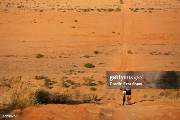 Stuart Wigfall of London, England pushes his bike up a hill during the morning stage of day three of the Simpson Desert Bike Challenge race on...