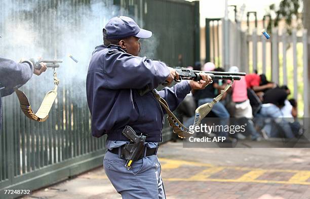 South African police fire rubber bullets and stun granades towards some 200 students trying to pull down a main entrance gate at the University on...