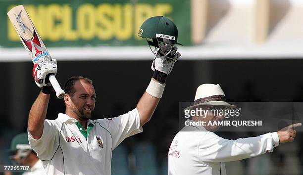 South African batsman Jacques Kallis raises his bat and helmet after scoring a century against Pakistan during the fourth day of the second Test...