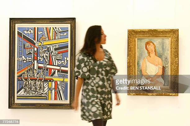 Visitor walks past Fernand Leger's 'Etude pour les constructeurs, fond bleu' and Amedeo Modigliani's 'Jeune fille assise en chemise' at Christie's in...