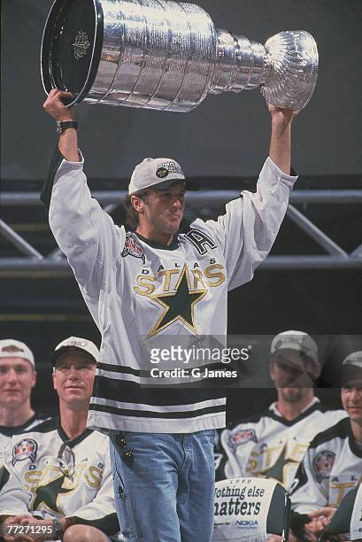 American ice hockey player Mike Modano of the Dallas Stars lifts the Stanley Cup over his head at a team celebration following the Stars' victory...