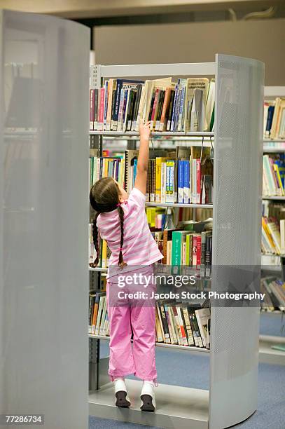 girl reaching for book in library - kids reaching shelf stock pictures, royalty-free photos & images