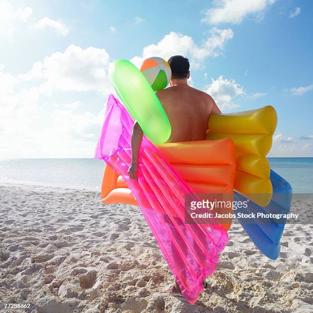 man carrying rafts on beach - airbed stock pictures, royalty-free photos & images