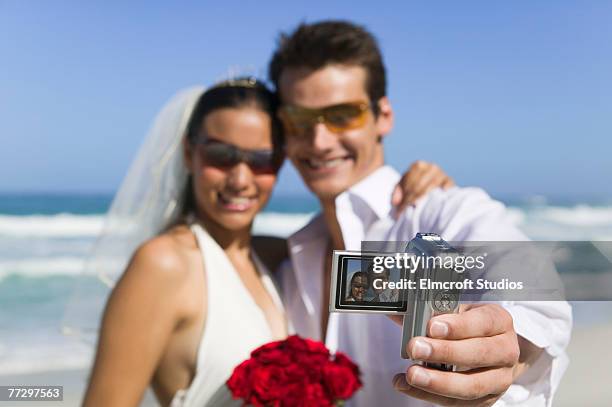 newlyweds taking photos on beach - photographie numérique photos et images de collection