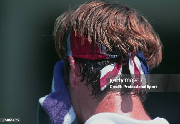 Canadian born British tennis player Greg Rusedski, wearing a union flag headband, wipes his face with a towel during competition to reach the fourth...