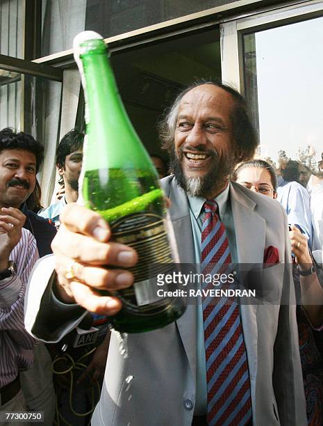 Chairman of the Intergovernmental Panel on Climate Change Rajendra Pachauri is watched by students as he holds a bottle of champagne after winning...