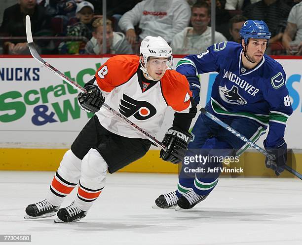 Daniel Briere of the Philadelphia Flyers and Willie Mitchell of the Vancouver Canucks skate up ice during their game at General Motors Place on...