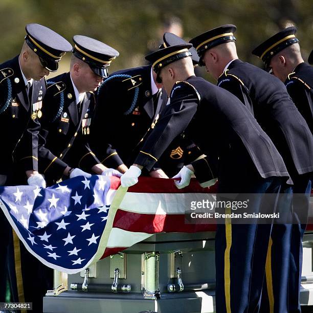 Soldiers fold an American flag above a casket containing the remains of soldiers who died in a helicopter crash earlier this year is brought to a...